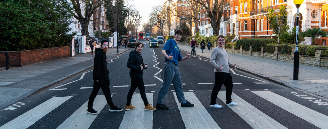 Students on a field trip recreating an album cover by The Beatles on the zebra crossing outside Abbey Road Studios in London