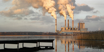 Large body of water with a fossil fuel power station emitting pollutants in the background