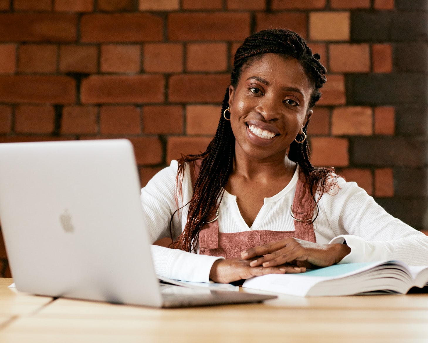 Student sat at a desk with a laptop in front of her, smiling