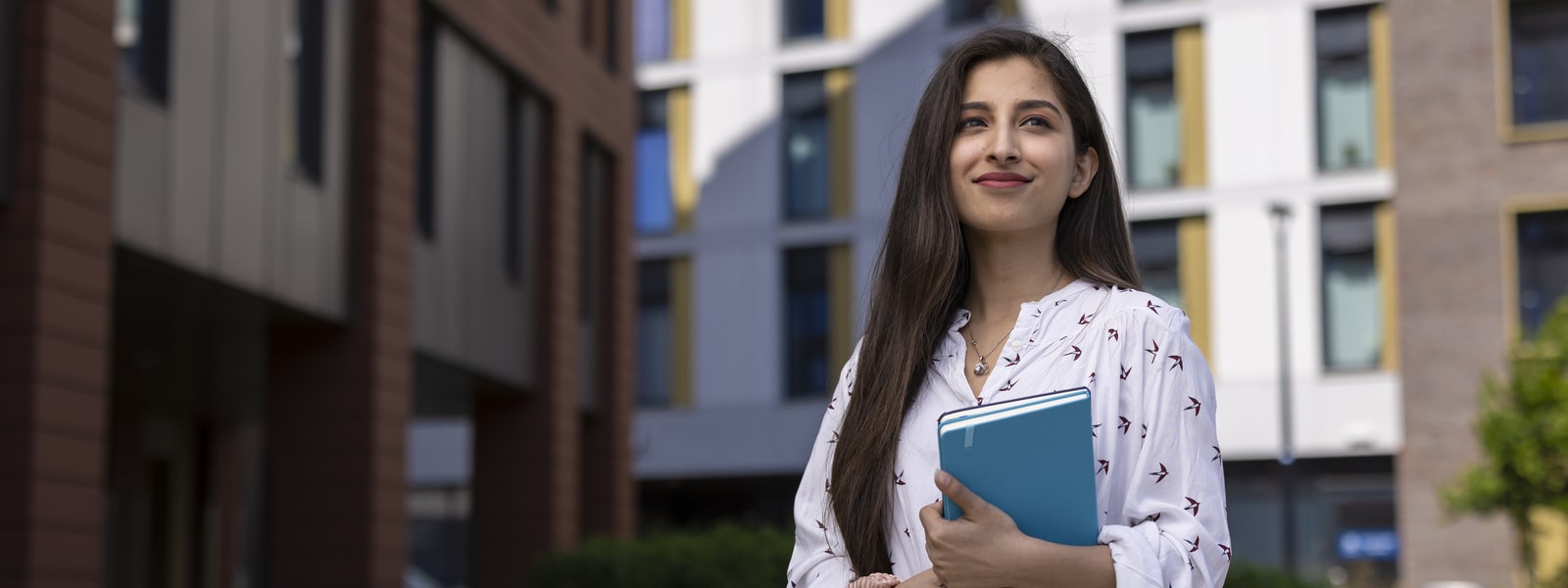 A student outside of University of Lincoln accommodation holding a diary